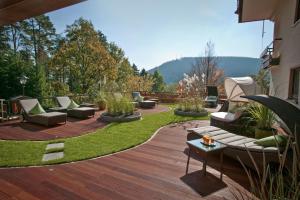 a patio with couches and chairs on a wooden deck at Wellnesshotel Sonnenhalde Tonbach in Baiersbronn
