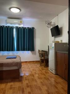 een kamer met een bed, een koelkast en een raam bij Zappa Guesthouse in Pattaya