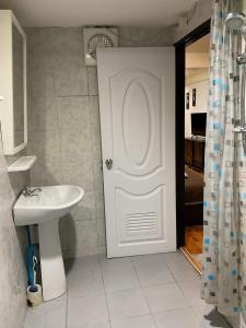 ein Badezimmer mit einer weißen Tür und einem Waschbecken in der Unterkunft Zappa Guesthouse in Pattaya