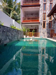 a swimming pool in front of a house at Cara White House in Galle