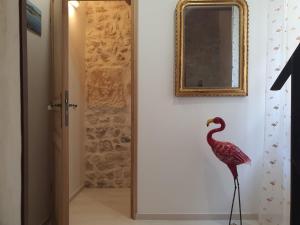 un pájaro rosa parado en un pasillo con un espejo en H2o Chambres d'Hôtes, en Peyriac-de-Mer