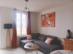 een woonkamer met een bank en een tafel bij La Maison des Magnolias in Trouville-sur-Mer