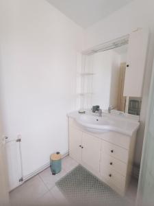 een witte badkamer met een wastafel en een spiegel bij La Maison des Magnolias in Trouville-sur-Mer