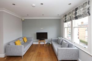 a living room with two couches and a flat screen tv at Bright and Modern 2 bed flat in London