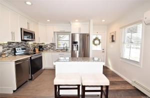 a kitchen with white cabinets and a kitchen island with stools at Romance Vacation Sweet Home 