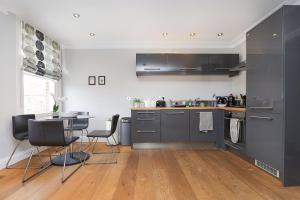 une cuisine avec des placards gris, une table et des chaises dans l'établissement Bright and Modern 2 bed flat, à Londres