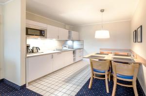 cocina con armarios blancos, mesa y sillas en Aparthotel Zingst, en Zingst