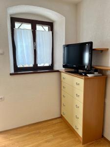 ein Zimmer mit einem Fernseher auf einer Kommode und einem Fenster in der Unterkunft Studio Centar in Cres
