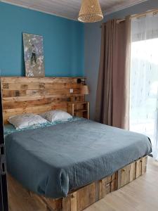 1 dormitorio con cama de madera y pared azul en Home Relax Perche : gîte avec prestations bien-être en Montigny-le-Chartif