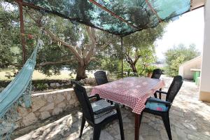 a table and chairs on a patio with a hammock at Apartments Davorka Šimuni in Šimuni