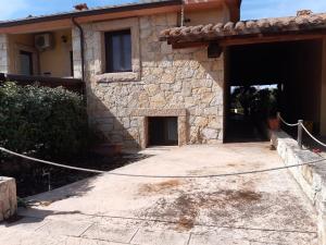 a large stone house with a garage and a driveway at Casa S'arena in Putzu Idu
