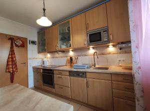 Una cocina con armarios de madera, fregadero y microondas. en Erholungsapartment, en Bad Lippspringe