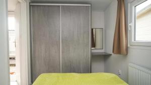 a bedroom with a wooden closet with a yellow bed at domek kempingowy in Chałupy