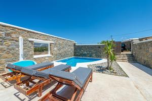 eine Villa mit einem Pool und Gartenmöbeln in der Unterkunft Manolia View Mykonos in Tourlos