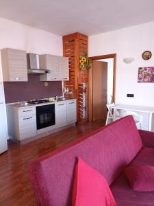 ein Wohnzimmer mit einem lila Sofa und einer Küche in der Unterkunft Trilocale centrale in Seregno