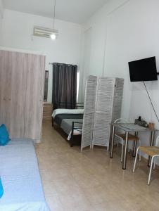 a room with a bed and a table and a television at Studio Jim in Volos