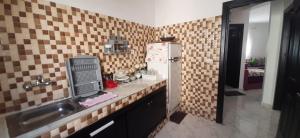 a tiled kitchen with a sink and a refrigerator at RESIDENCE AL Hoceima 2 Minutes de prés de PLAGE CALABONITA in Al Hoceïma