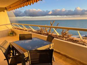 una mesa y sillas en un balcón con vistas al océano en 06AO - Superbe appartement avec vue mer exceptionnelle, en Villeneuve-Loubet