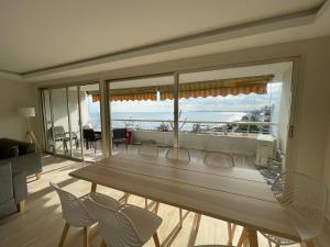 una mesa y sillas en una sala de estar con una gran ventana en 06AO - Superbe appartement avec vue mer exceptionnelle, en Villeneuve-Loubet