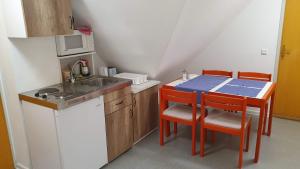 una pequeña cocina con fregadero y mesa con sillas en Aszófői Panoráma Apartmanház, en Aszófő