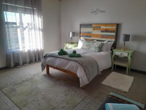 a bedroom with a large bed with a wooden headboard at Camelot Cottages in Langebaan