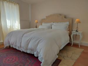 1 dormitorio con 1 cama grande con sábanas y almohadas blancas en Romantisches Ferienhaus in Moselnähe, en Maring-Noviand