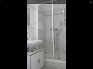 een witte badkamer met een douche en een wastafel bij Chez Lulu in Montreuil