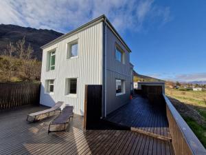 Una casa en una terraza con un banco. en Sólgarður Guesthouse, en Bíldudalur
