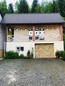 a white house with two garage doors and a driveway at Під лісом in Soymy