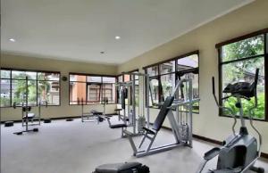 a gym with treadmills and ellipticals and windows at Apartment 6162 at Jayakarta Residence Bali in Seminyak