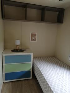 ein Schlafzimmer mit einem Bett und eine Kommode mit einer Lampe in der Unterkunft Charmant mobil-home in Rocbaron