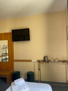 シャトーヌフ・シュル・ロワールにあるHôtel La Capitainerieのベッド1台と壁掛けテレビが備わる客室です。
