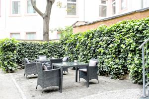 un gruppo di sedie e un tavolo di fronte ad una siepe di TOWNHOUSE Hotel a Francoforte sul Meno