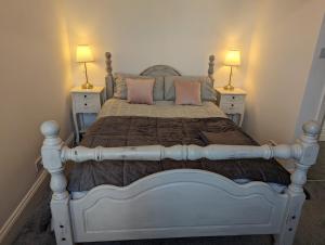 - une chambre avec un lit avec des oreillers roses et 2 lampes dans l'établissement Cosy Bee, à Bournemouth