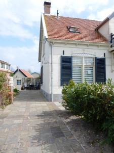 
a white house with a blue door and windows at De Waterlelie in Renesse
