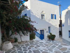 a street with white buildings with blue doors and flowers at Octopus Suites Parikia in Parikia