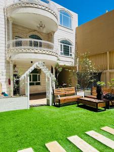 a house with a lawn with benches and an arbor at Happy Day هابي دي 