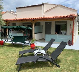 ein Paar Gartenstühle vor einem Haus in der Unterkunft Harmony Studios & Apartments in Skala Potamias