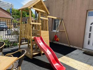 a wooden playset with a red slide and a table at Pensiunea Ana Maria in Baile Felix