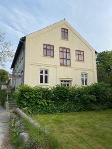 Sejerby的住宿－Sejerø Vandrehjem，一间大型白色房屋,设有红色窗户