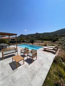 a swimming pool with two chairs and a table and a table at Casa Agatha : Villa avec piscine in Figari