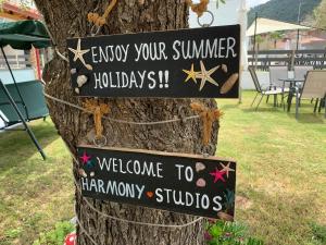 ein Schild auf einem Baum, auf dem steht: "Genießt eure Sommerferien." in der Unterkunft Harmony Studios & Apartments in Skala Potamias