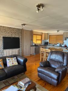 a living room with a leather couch and a kitchen at Makarios in Great Brak River