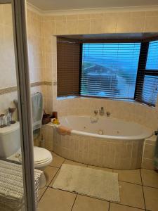 ein Bad mit einer Badewanne, einem WC und einem Fenster in der Unterkunft Makarios in Groot Brak Rivier