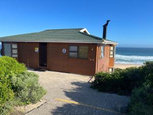 a wooden house with the ocean in the background at Makarios in Great Brak River