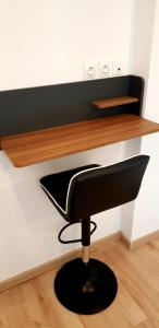 une chaise noire assise sous une étagère en bois dans l'établissement Escapade Niortaise - Studios climatisés hyper-centre de Niort, à Niort