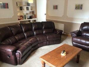 a living room with a brown leather couch and a coffee table at The Coffee Pot accommodation in Dufftown