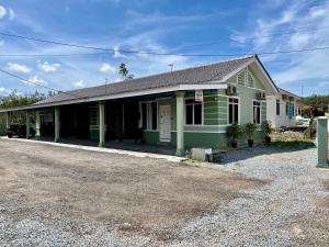 an old green and white building with a driveway at Aufa Roomstay in Pendang