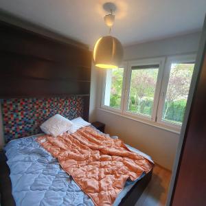 a bedroom with a bed with a comforter and two windows at Apartament Batorego 2a in Gdańsk