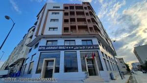 un grand bâtiment avec un panneau à l'avant dans l'établissement Hotel Jaouharat Ismaili, à Meknès